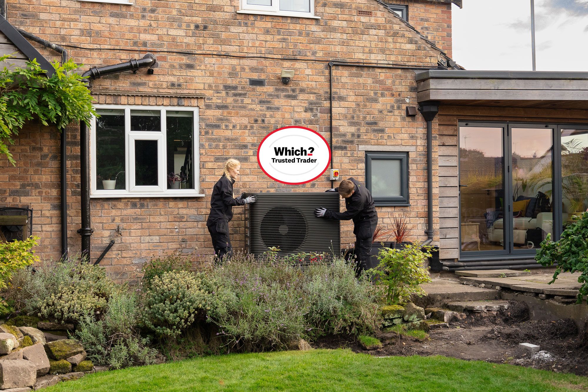 Two Aira Technicians installing an Aira heat Pump with a Which? Trusted Traders badge above them
